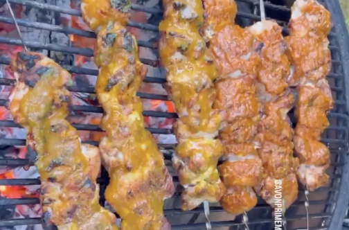Chicken thigh skewers lined up on grill.
